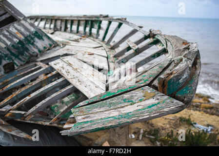 Barca abbandonata spiaggia, vista di un abbandonato barca da pesca lasciata decadere accanto il mare-muro a Marsala in Sicilia. Foto Stock