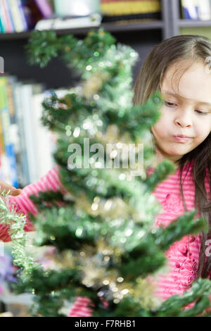 Ragazza giovane felicemente la decorazione albero di Natale Foto Stock