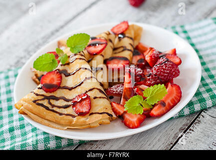 Pancake con fragole e cioccolato decorato con foglie di menta Foto Stock