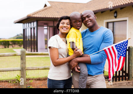 Ritratto di giovane azienda familiare bandiera americana al di fuori della loro casa Foto Stock