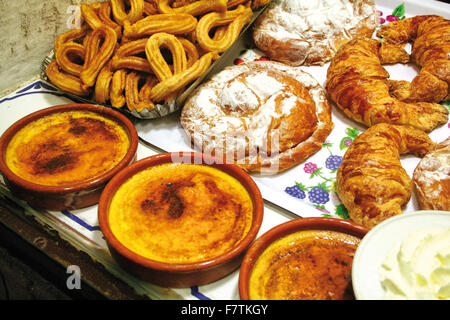 Crema catalana, popolare catalano crema fredda ricetta con un croccante caramello rivestimento. Sullo sfondo churros e ensaimadas Foto Stock