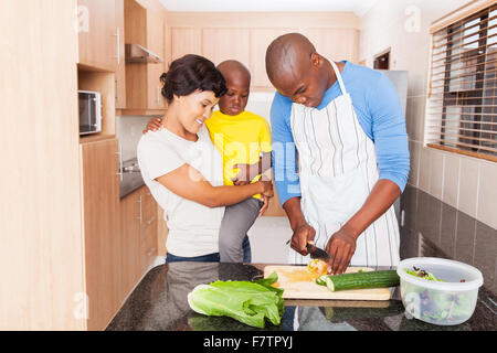 L'uomo africano rendendo insalata per famiglia in cucina domestica Foto Stock