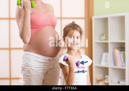 Gravidanza La madre e il bambino più anziano si impegnano nel fitness manubri Foto Stock