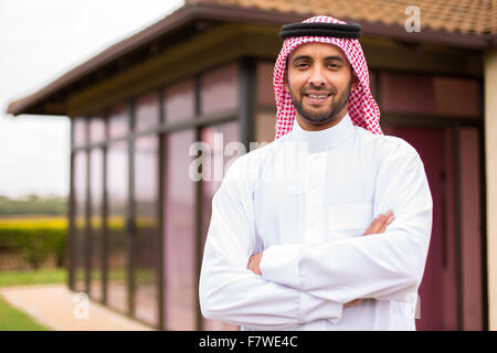 Moderno e giovane uomo arabo con le braccia incrociate al di fuori di casa sua Foto Stock