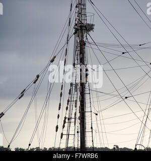 Una donna che sale l'albero di una nave a vela in condizioni di tempo nuvoloso scuro in Australia Foto Stock