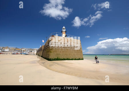 St Ives, Cornwall, Regno Unito: donna camminando lungo la spiaggia sottostante Smeaton è Pier Foto Stock