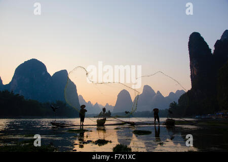 Cormorano Fisherman gettando al netto di pesce sul Fiume Li Regione Guilin Guangxi, Cina LA008323 Foto Stock