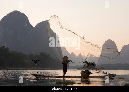 Cormorano Fisherman gettando al netto di pesce sul Fiume Li Regione Guilin Guangxi, Cina LA008327 Foto Stock