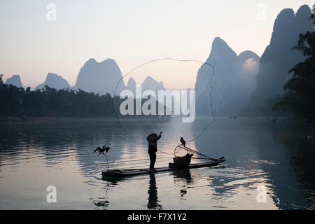 Cormorano Fisherman gettando al netto di pesce sul Fiume Li Regione Guilin Guangxi, Cina LA008328 Foto Stock