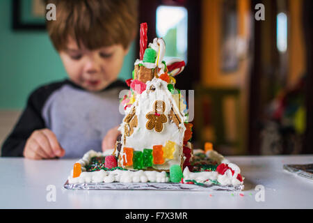 Gingerbread house con ragazzo mangiando caramelle in background Foto Stock