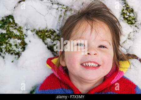 Ritratto di una ragazza distesa nella neve Foto Stock