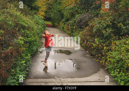 Ragazza di saltare in una pozzanghera Foto Stock