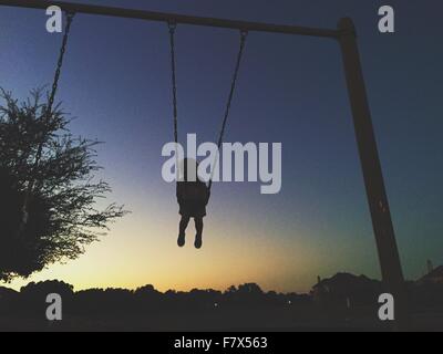 Silhouette di un bambino di swing in sunset Foto Stock