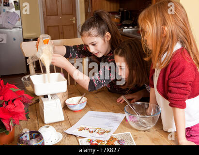 Peso dello zucchero. Tre giovani sorelle stanno rendendo pan di zenzero per i regali di Natale. Essi stanno lavorando insieme in modo cooperativo. Foto Stock