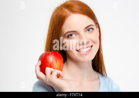 Ritratto di un felice redhead donna azienda apple isolato su uno sfondo bianco e guardando la fotocamera Foto Stock