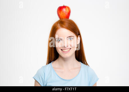 Ritratto di un sorridente redhead donna in piedi con Apple sulla testa isolata su una backgroun bianco Foto Stock