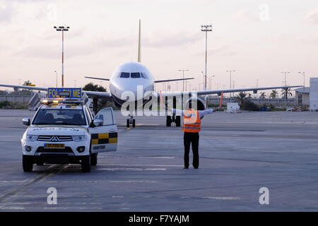 Un aeroplano Airbus A320-200 di Monarch Airlines è stato marshalled da un segnalatore utilizzando segnali a mano dopo l'atterraggio nell'aeroporto ben Gurion ampiamente noto come Lod Airp Foto Stock