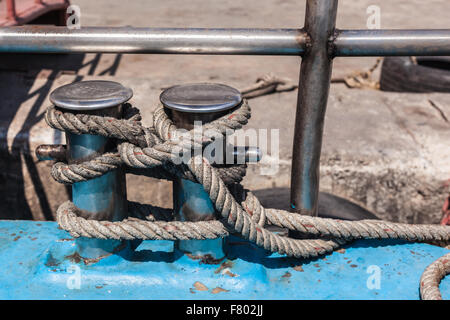 Immagine ravvicinata di un grande bollard con una corda legata a essa Foto Stock