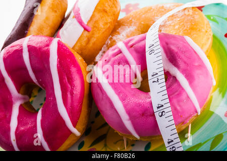 Alcuni deliziosi e ciambelle colorate con nastro di misurazione Foto Stock