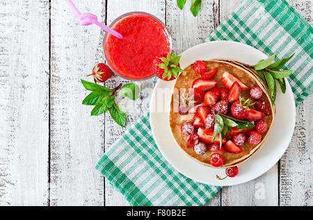 Frittelle con bacche e frullato fragole in uno stile rustico. Vista superiore Foto Stock