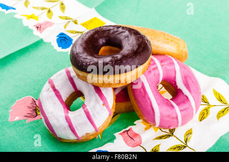 Alcuni deliziosi e ciambelle colorate su una verde ornato tovaglia Foto Stock