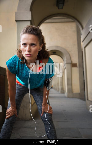 Sportivo da donna con auricolari cattura respiro dopo un sano jogging a Firenze, Italia Foto Stock