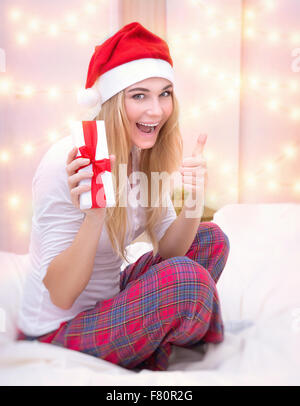 Gioiosa Santa ragazza ricevere dono festivo, godendo grande la mattina di Natale, gesti di buon umore dal pollice in alto, vacanze felici Foto Stock