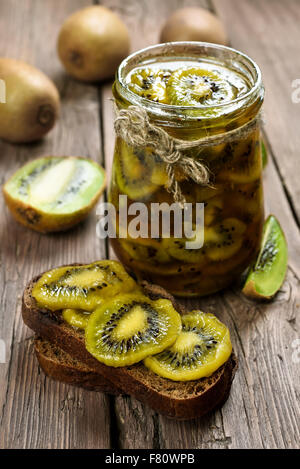 Deliziosa marmellata di kiwi sul tavolo di legno. Focus su kiwi fette di pane Foto Stock