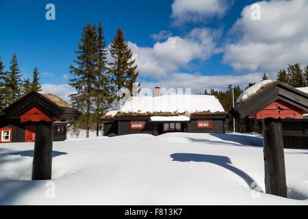 Tradizionale baita norvegese circondato da neve profonda con due pilastri con un cielo blu Foto Stock