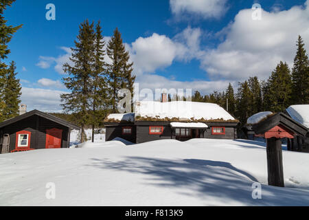 Tradizionale baita norvegese circondato da neve profonda con un cielo blu Foto Stock