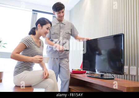 Ingegnere riparazione di televisione nella casa del cliente Foto Stock