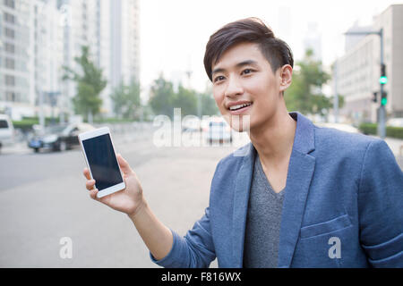 Giovane uomo in attesa di taxi con smart phone Foto Stock