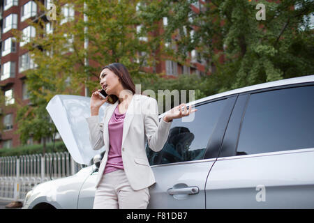 Proprietario auto parlando al telefono accanto a ripartiti in auto Foto Stock