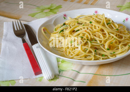 Un piatto di spaghetti con le vongole (pasta e rivendicazioni) una forcella rossa e un coltello bianco, tipico di pesce italiano Foto Stock