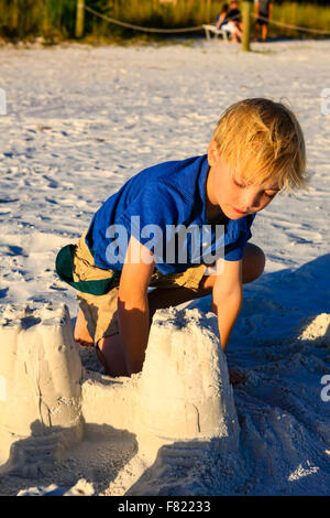 Ragazzo che pongono al tramonto dal castello di sabbia ha costruito sulla Siesta Key Beach in Florida Foto Stock