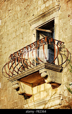 Architettura dettaglio con un arrugginito ferro battuto balcone sulla facciata di una casa abbandonata Foto Stock