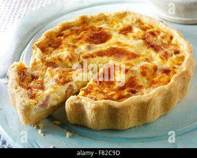 Tutto quiche Loraine in un ora di pranzo impostazione con una fetta tagliata Foto Stock