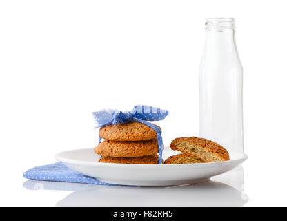 Pila di tre in casa i fiocchi d'avena cookie legate con nastro blu e metà dei cookie su piastra bianca e vuoto bottiglia di latte Foto Stock