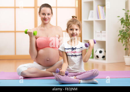 Gravidanza mamma e bambino più anziano si impegnano nel fitness manubri Foto Stock