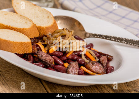 Tradizionale in rosso i fagioli con salsiccia e verdure e baguette Foto Stock