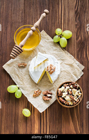 Formaggio Camembert con noci, miele e Uva su carta pergamena Foto Stock