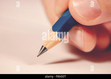 Macro colpo di mano maschio scrivere note con matita su un pezzo di carta, il fuoco selettivo Foto Stock