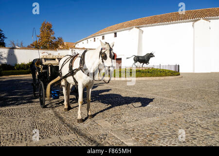 Carrozza a cavallo e la statua di bronzo fighting Bull, Toro, di fronte a Plaza de Toros de Ronda, Bullring, Andalusia, Spagna Foto Stock