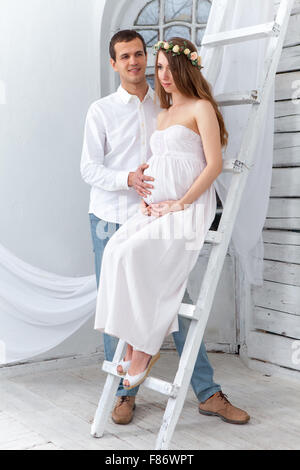 Allegro coppia giovane vestito di bianco in piedi a casa Foto Stock