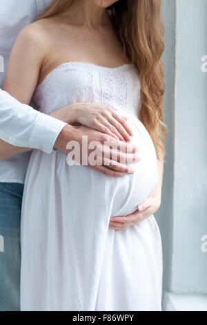 La giovane coppia vestita di bianco in piedi a casa Foto Stock