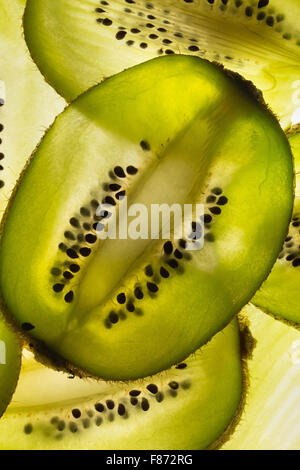 Esotica frutta kiwi retroilluminato in studio il taglio trasversale e longitudinale che mostra le sezioni interne di distribuzione di sementi intorno al nucleo centrale Foto Stock