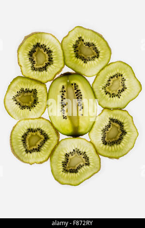 Esotica frutta kiwi retroilluminato in studio il taglio trasversale e longitudinale che mostra le sezioni interne di distribuzione di sementi intorno al nucleo centrale Foto Stock