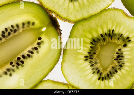 Esotica frutta kiwi retroilluminato in studio il taglio trasversale e longitudinale che mostra le sezioni interne di distribuzione di sementi intorno al nucleo centrale Foto Stock