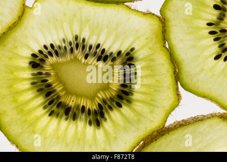 Esotica frutta kiwi retroilluminato in studio il taglio trasversale e longitudinale che mostra le sezioni interne di distribuzione di sementi intorno al nucleo centrale Foto Stock