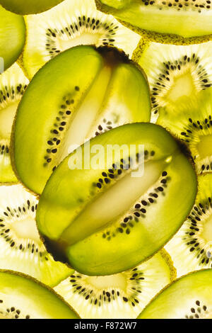 Esotica frutta kiwi retroilluminato in studio il taglio trasversale e longitudinale che mostra le sezioni interne di distribuzione di sementi intorno al nucleo centrale Foto Stock